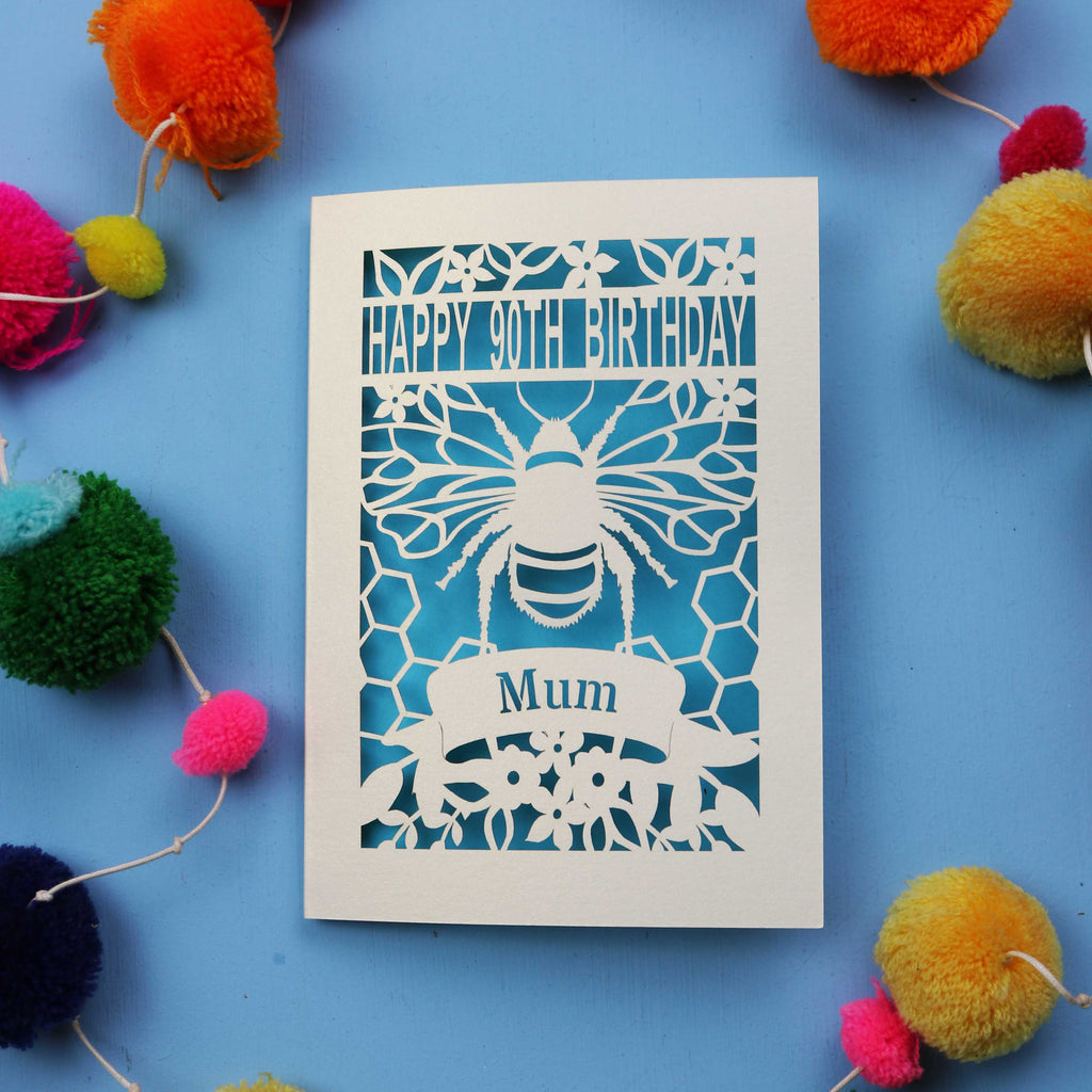 90th Birthday card with bee design and colourful pom-poms on a blue background
