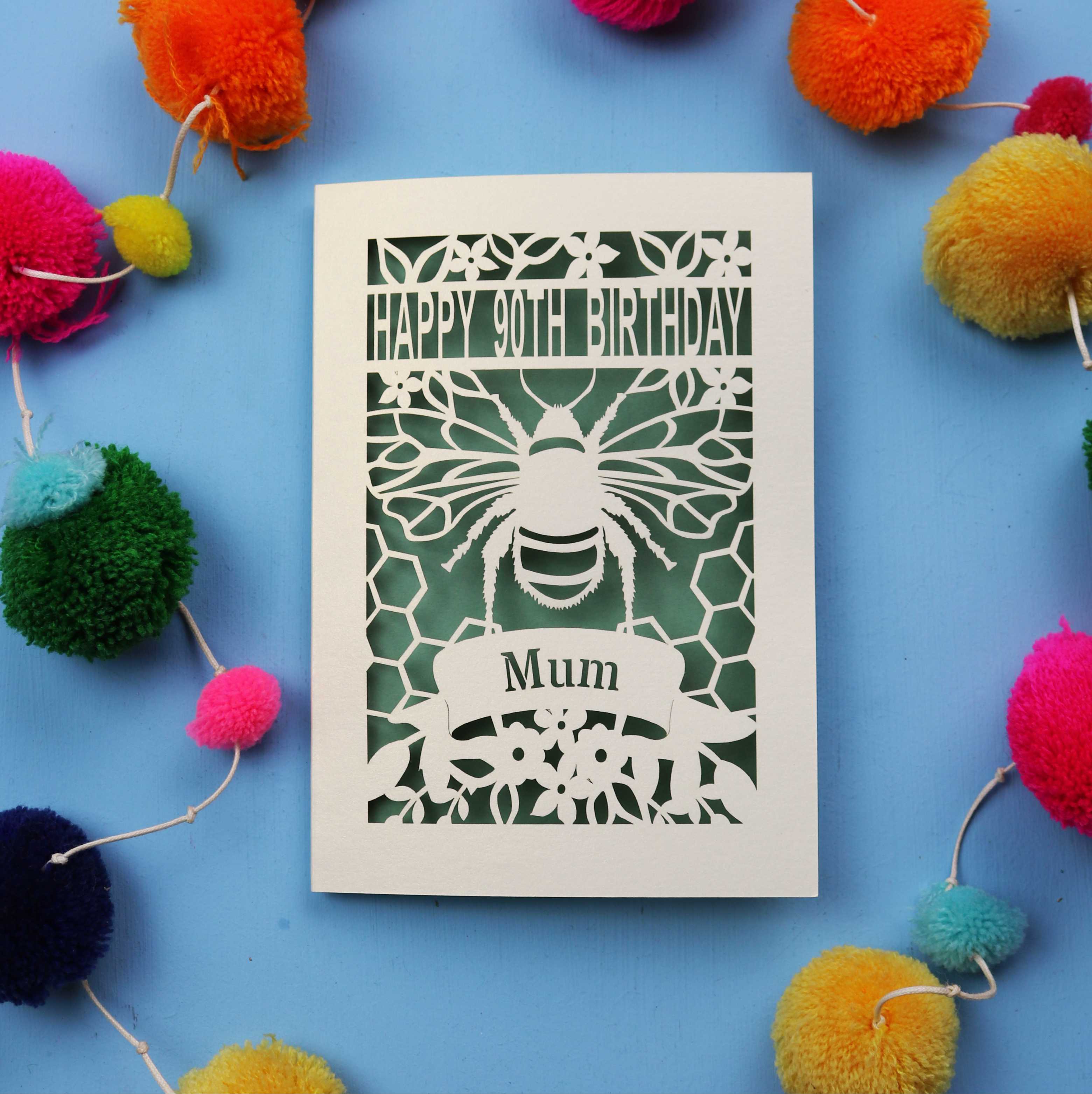 90th Birthday card with bee design and colourful pom-poms on a blue background