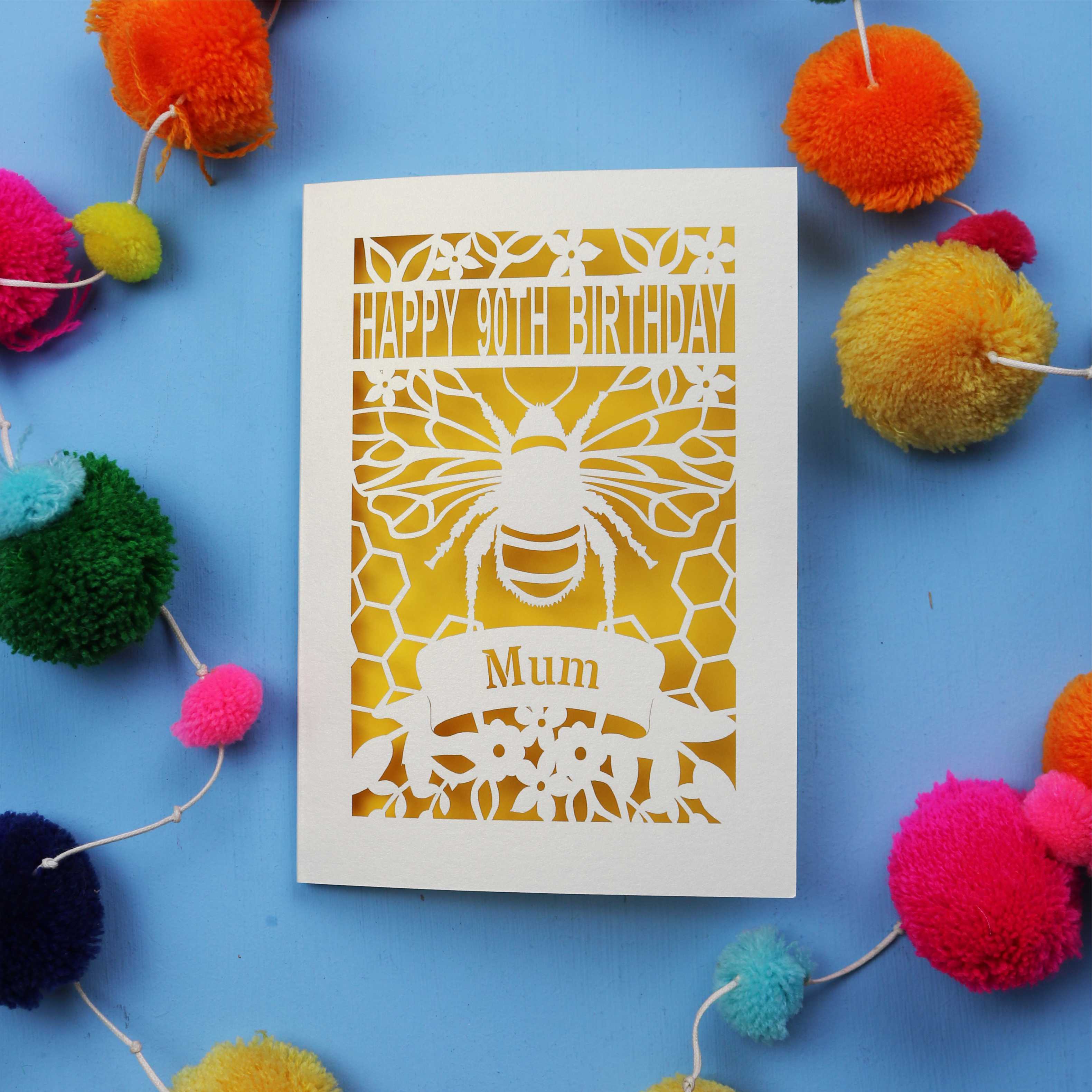90th Birthday card with bee design and colourful pom-poms on a blue background