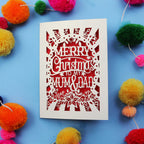 Laser cut Christmas card with 'Merry Christmas to my Mum & Dad' text on a blue background with colourful pom-poms.