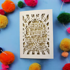 Laser cut Christmas card with 'Merry Christmas to my Mum & Dad' text on a blue background with colourful pom-poms.
