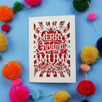 Christmas card with 'Merry Christmas to my Mums' text surrounded by colourful pom-poms on a blue background