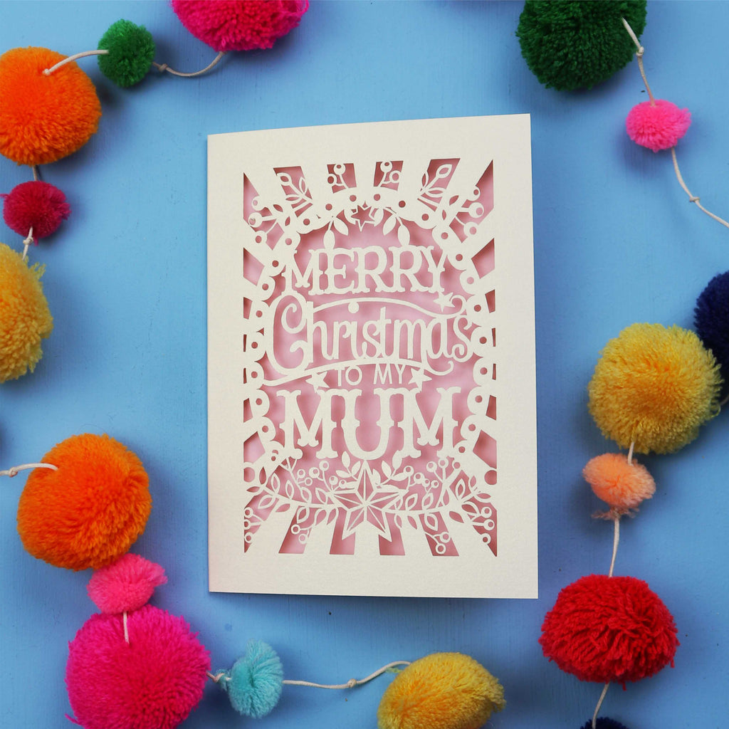 Decorative Christmas card with 'Merry Christmas to my Mum' text on a blue background with colourful pom-poms.