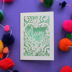 A cream and light green mother's day card with "Mum" written inside a heart shape