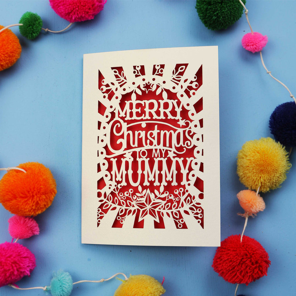 Laser cut Mummy Christmas card with 'Merry Christmas to my Mummy' text on a blue background with colourful pom-poms.