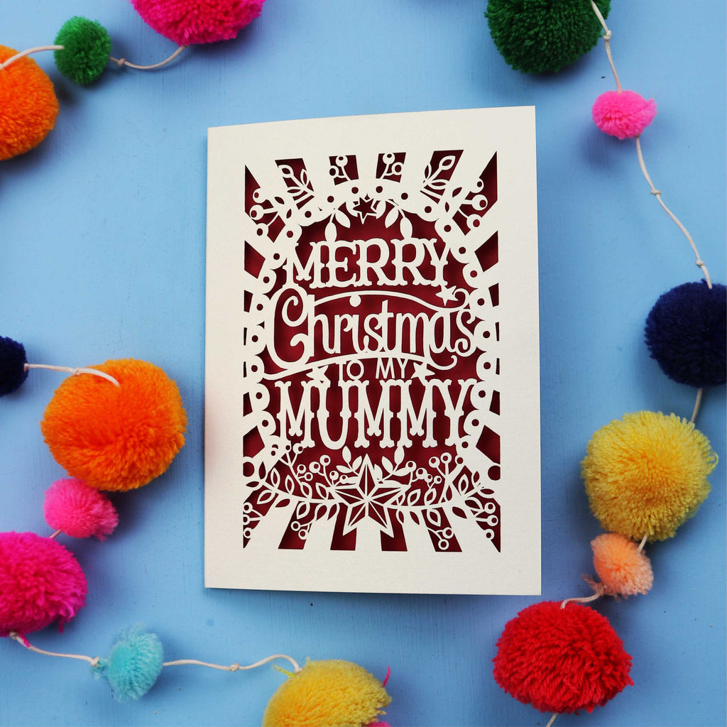 Laser cut Mummy Christmas card with 'Merry Christmas to my Mummy' text on a blue background with colourful pom-poms.