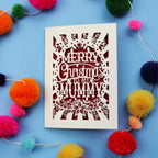Laser cut Mummy Christmas card with 'Merry Christmas to my Mummy' text on a blue background with colourful pom-poms.