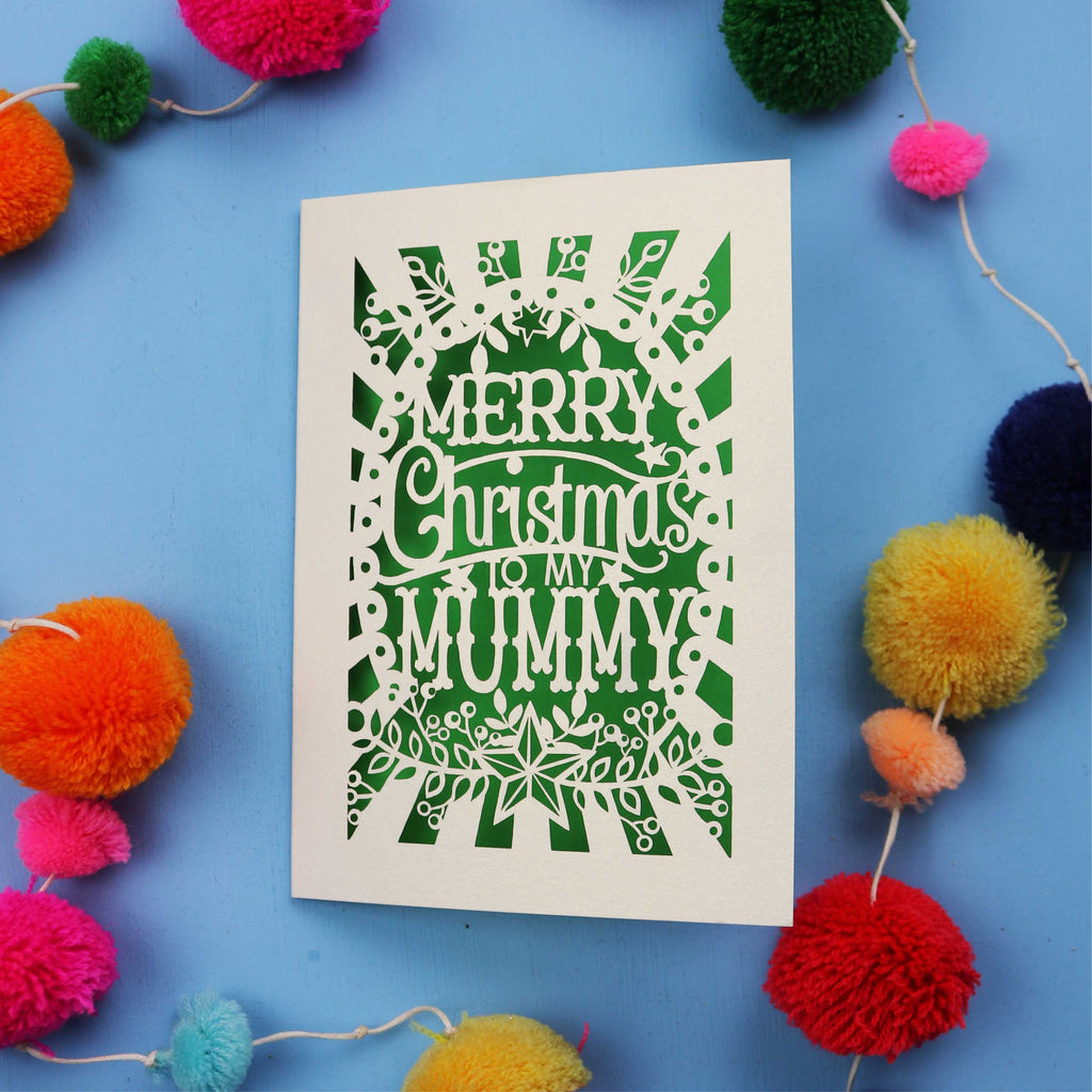 Laser cut Mummy Christmas card with 'Merry Christmas to my Mummy' text on a blue background with colourful pom-poms.