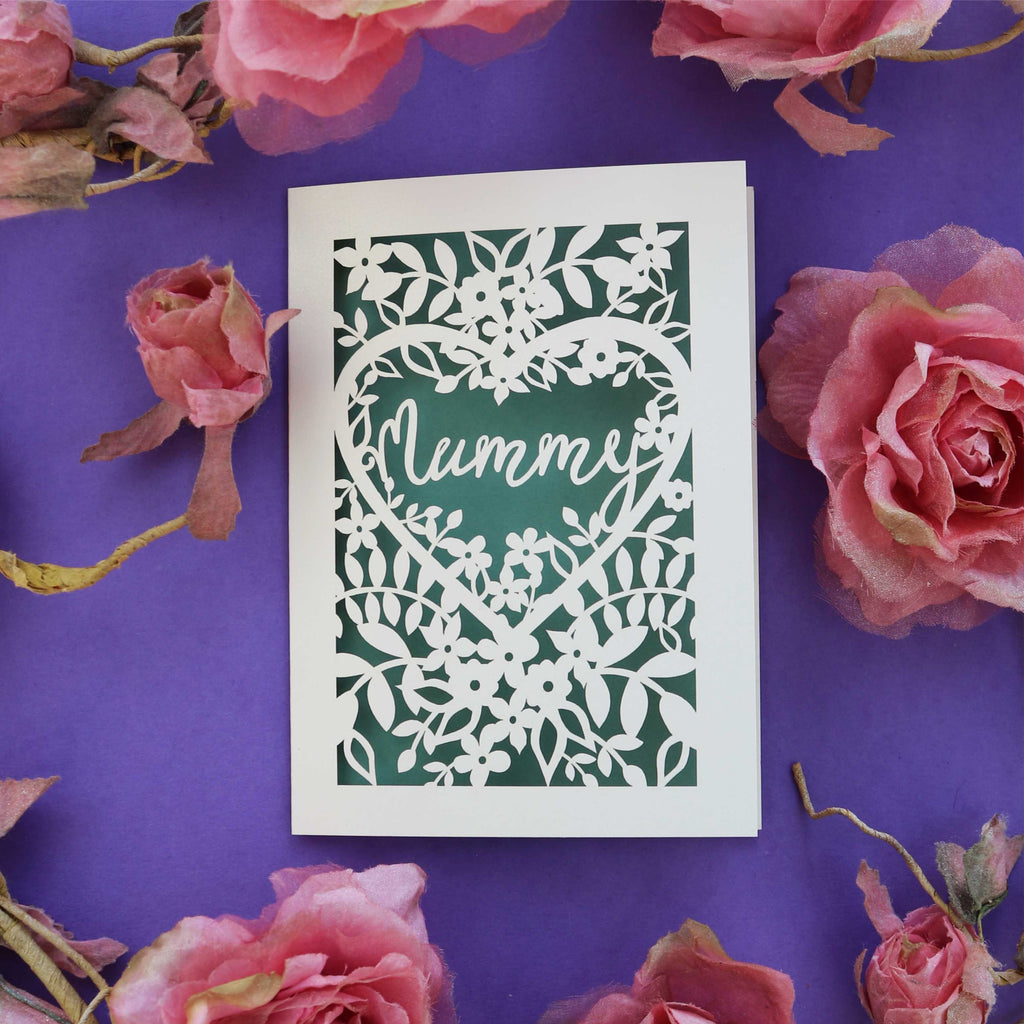 A laser cut mother's day card that says "mummy" inside a heart, surrounded by flowers.
