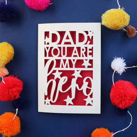  A laser cut Father's Day card that says "Dad, you are my hero". The laser cut text is cream and surrounded by satrs, with a red paper backing behind