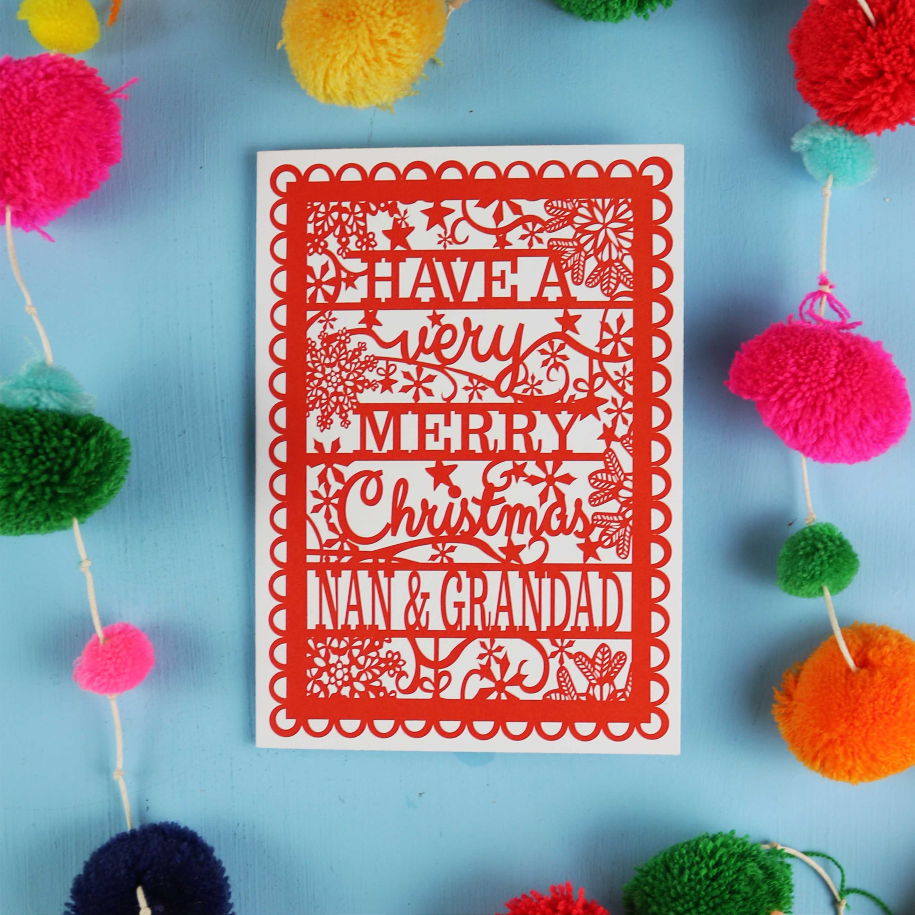 Red Christmas card with personalized message on a blue background with colourful pom-poms.