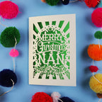 Christmas card with 'Merry Christmas Nan' text surrounded by colourful pom-poms on a blue background