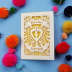 Personalised baby card with personalised name and date, and intricate laser cut design on a blue background with colourful pom-poms.
