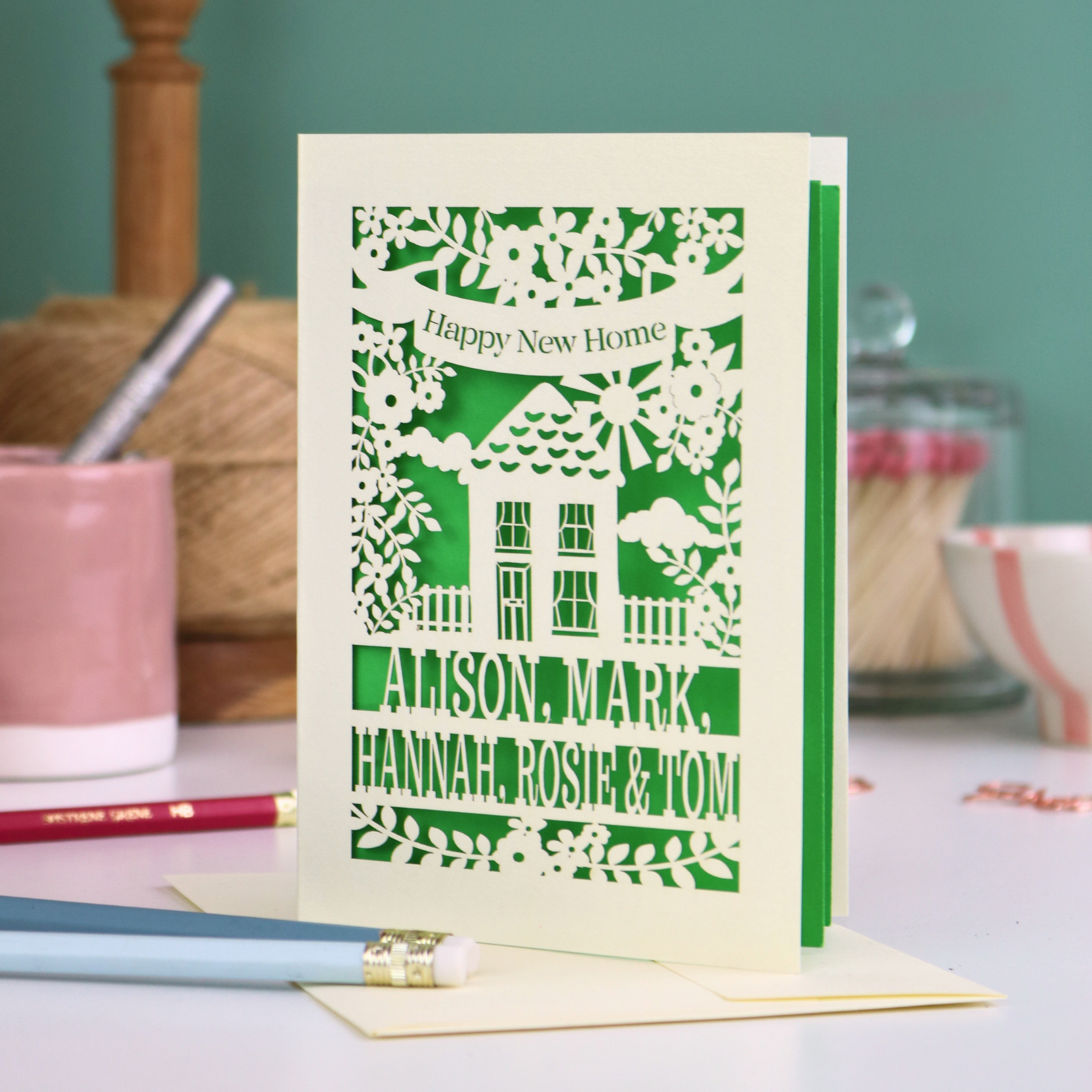 Decorative greeting card with house design and text on a table with stationery items.
