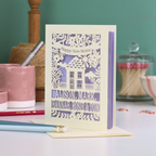 Greeting card with 'Happy New Home' message on a table with stationery items.