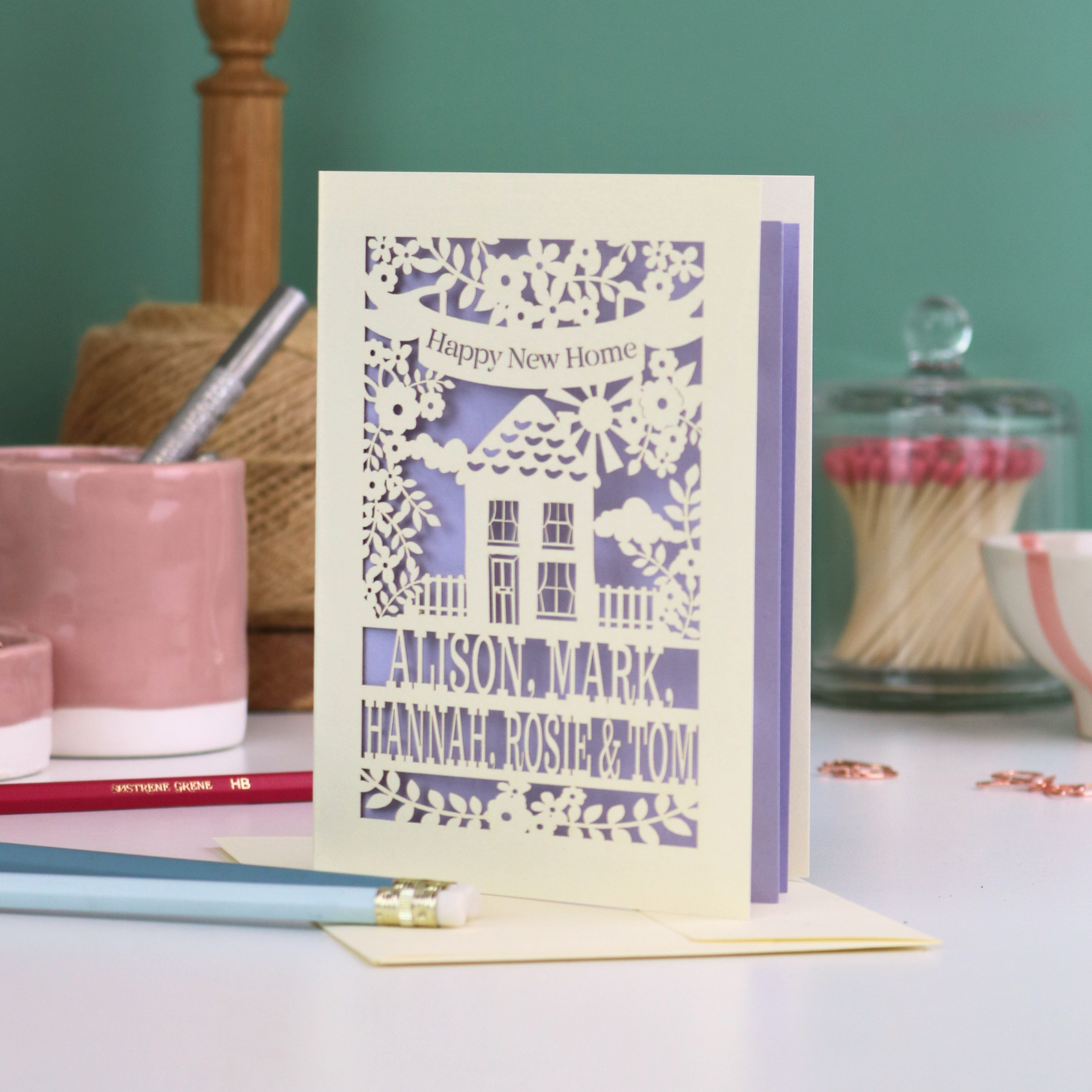 Greeting card with 'Happy New Home' message on a table with stationery items.