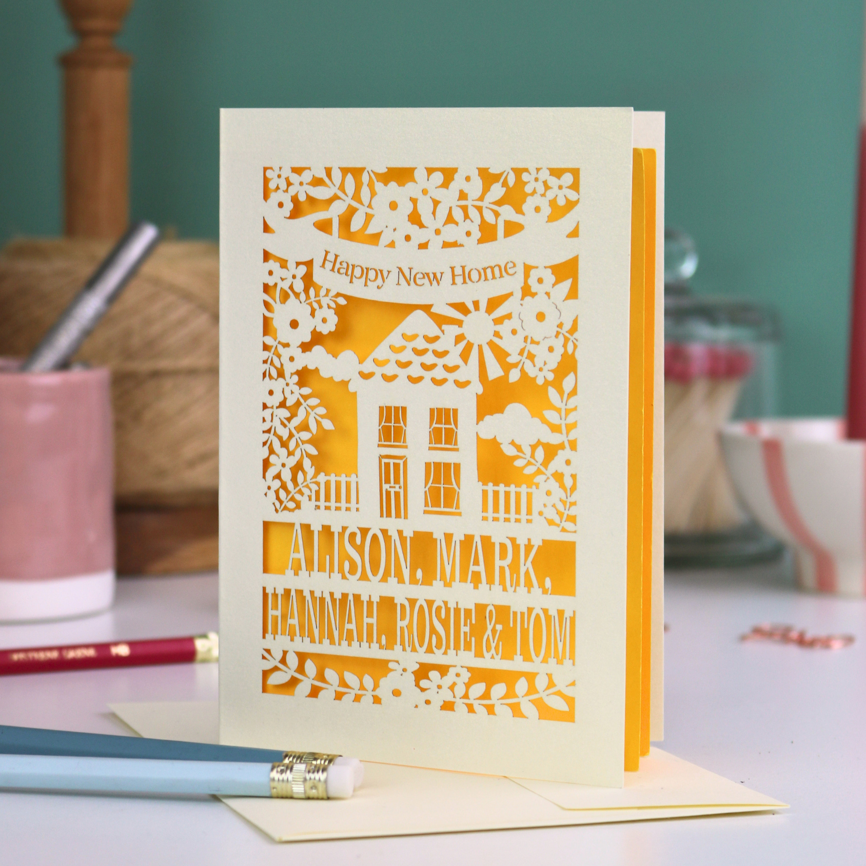 Greeting card with laser-cut design and text on a table with stationery items.