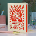 A laser cut new home card with cut out swallow design and text in a banner, "There's no place like home"