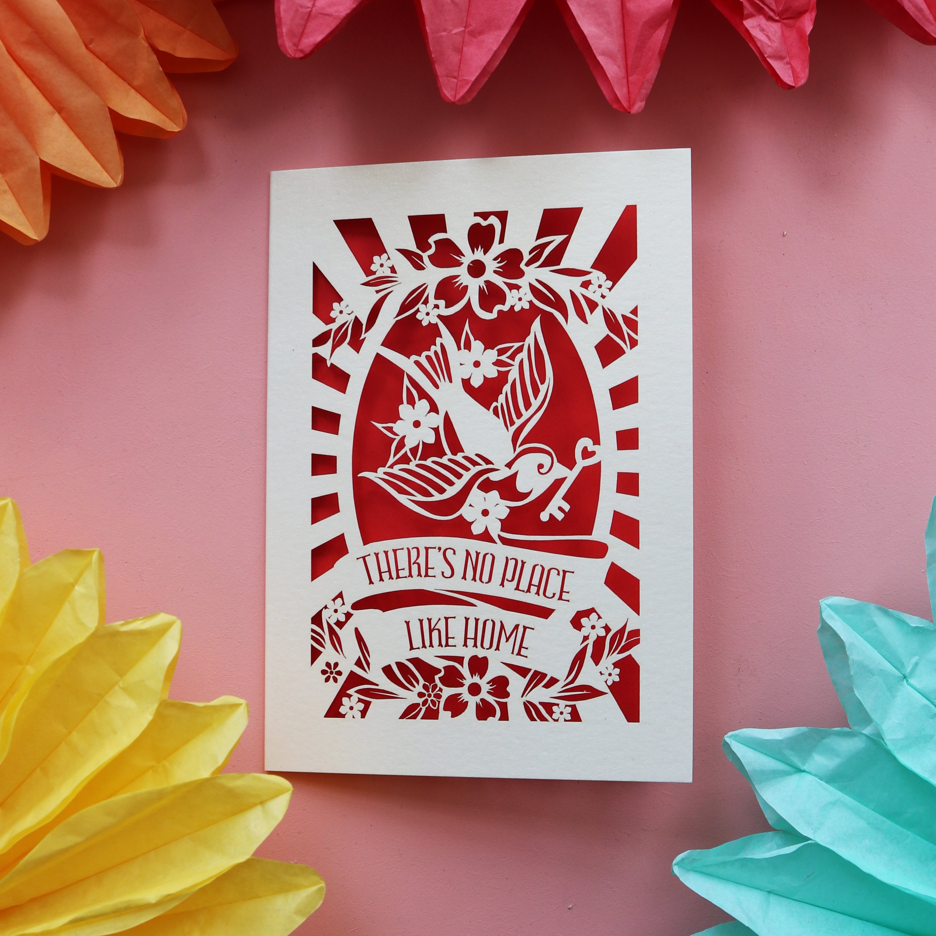 A laser cut new home card with a bird holding a key, and the words "There's no place like home"
