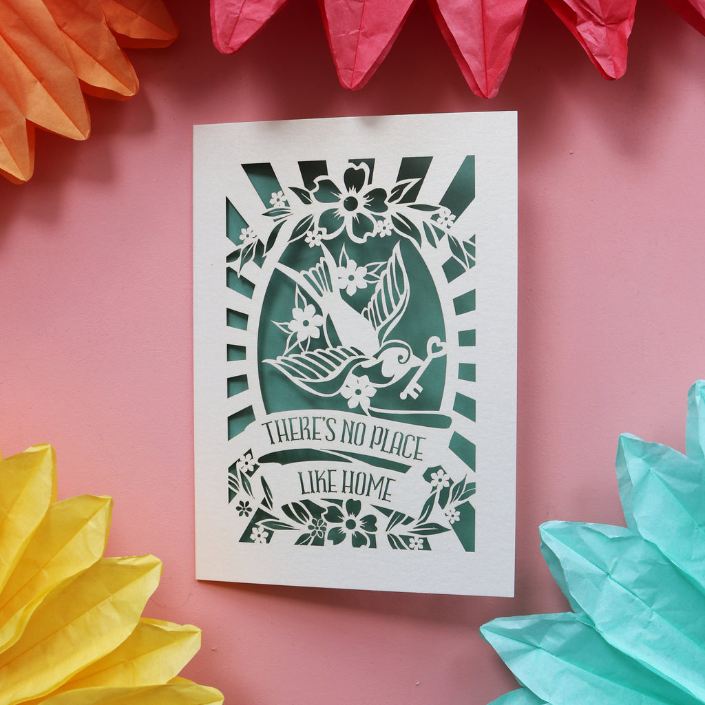A special card for new home featuring a bird holding a key and the words "There's no place like home."