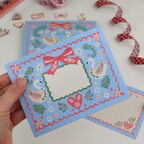 Decorative envelope with swan design held by a hand on a white background
