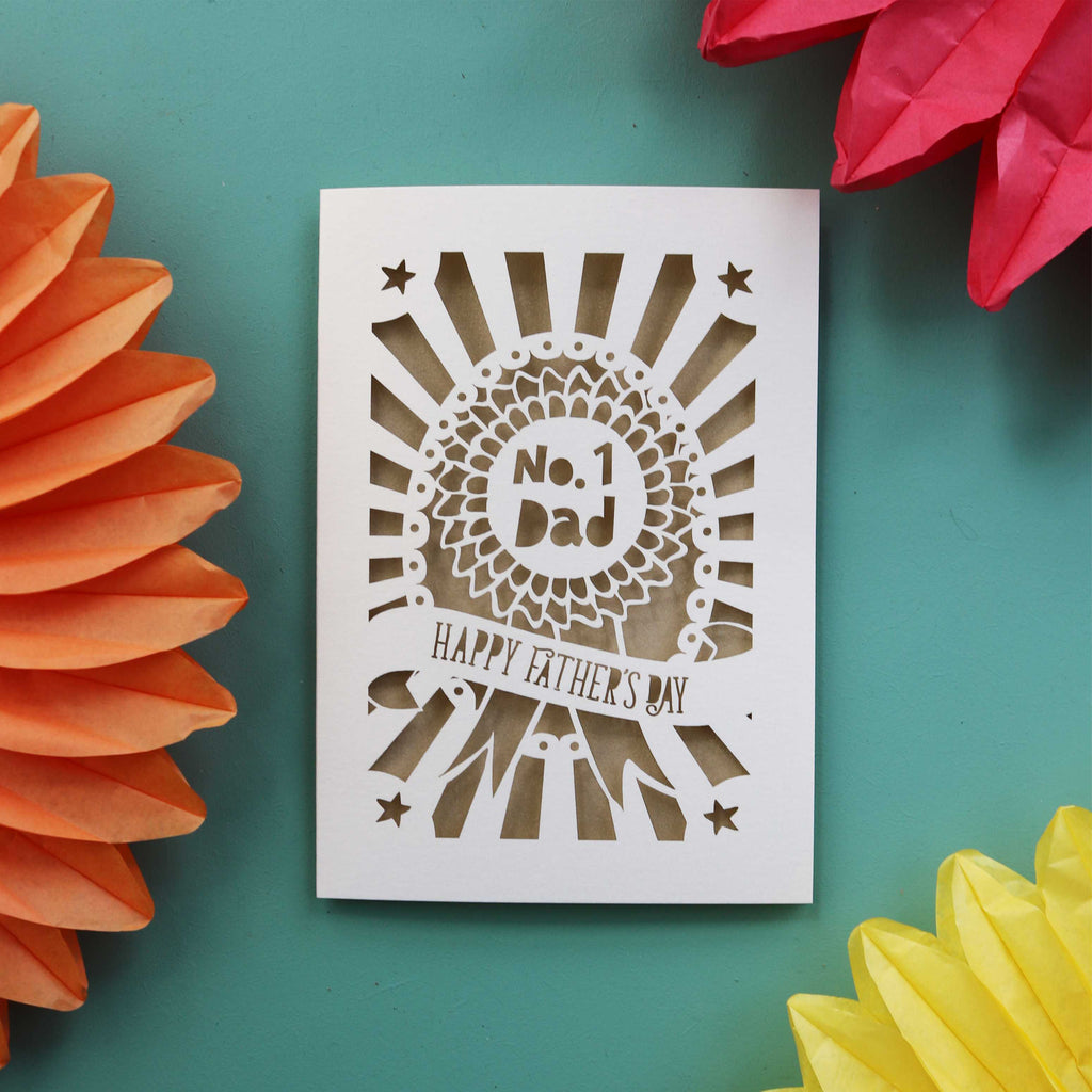 A cream and gold paper cut card for Father's Day, featuring a rosette with the words "No. 1 Dad"