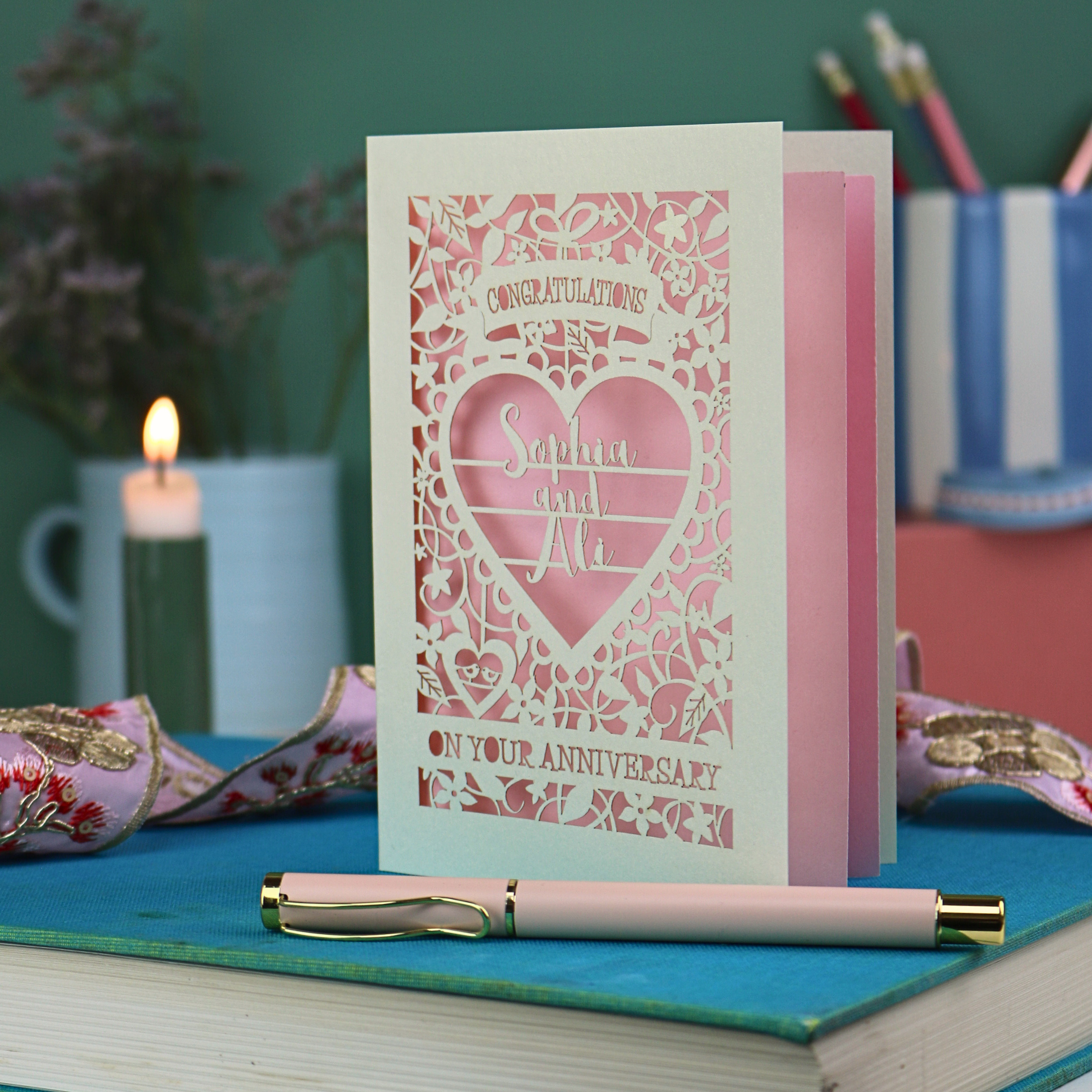 Anniversary card with decorative heart design on a table with stationery items.