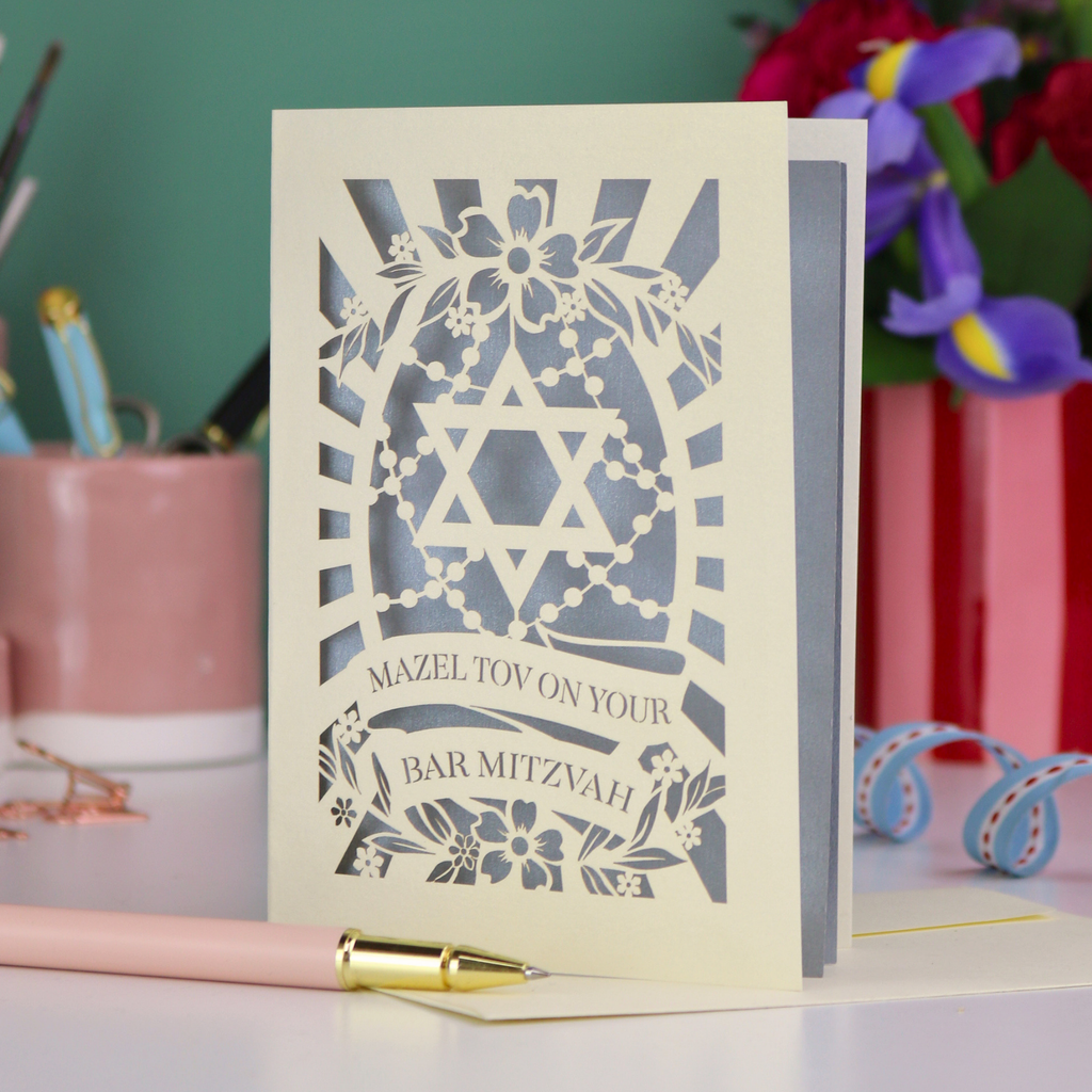 Bar Mitzvah card with Star of David design on a table with stationery items.
