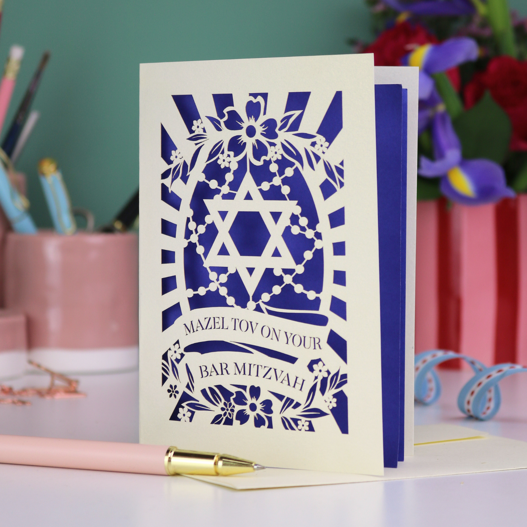 Bar Mitzvah card with blue and white design on a desk with stationery items.