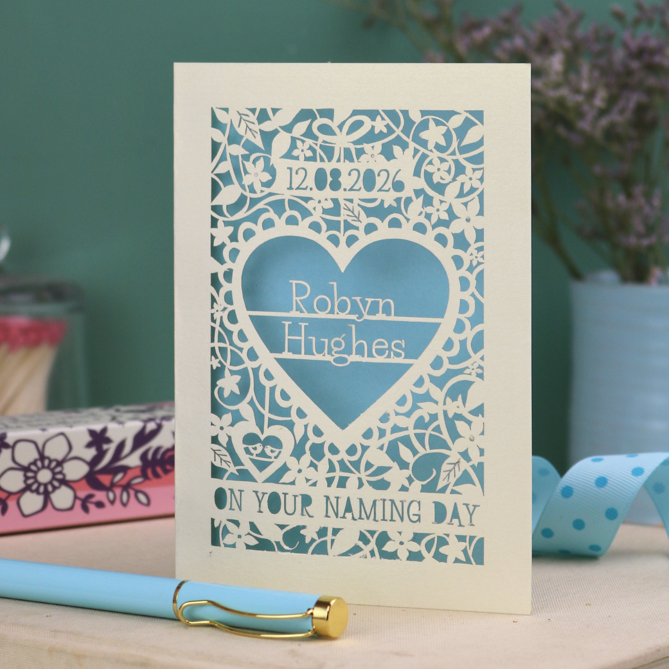Paper cut "on your naming day" card personalised with the date and the name of the recipient, with a floral heart border