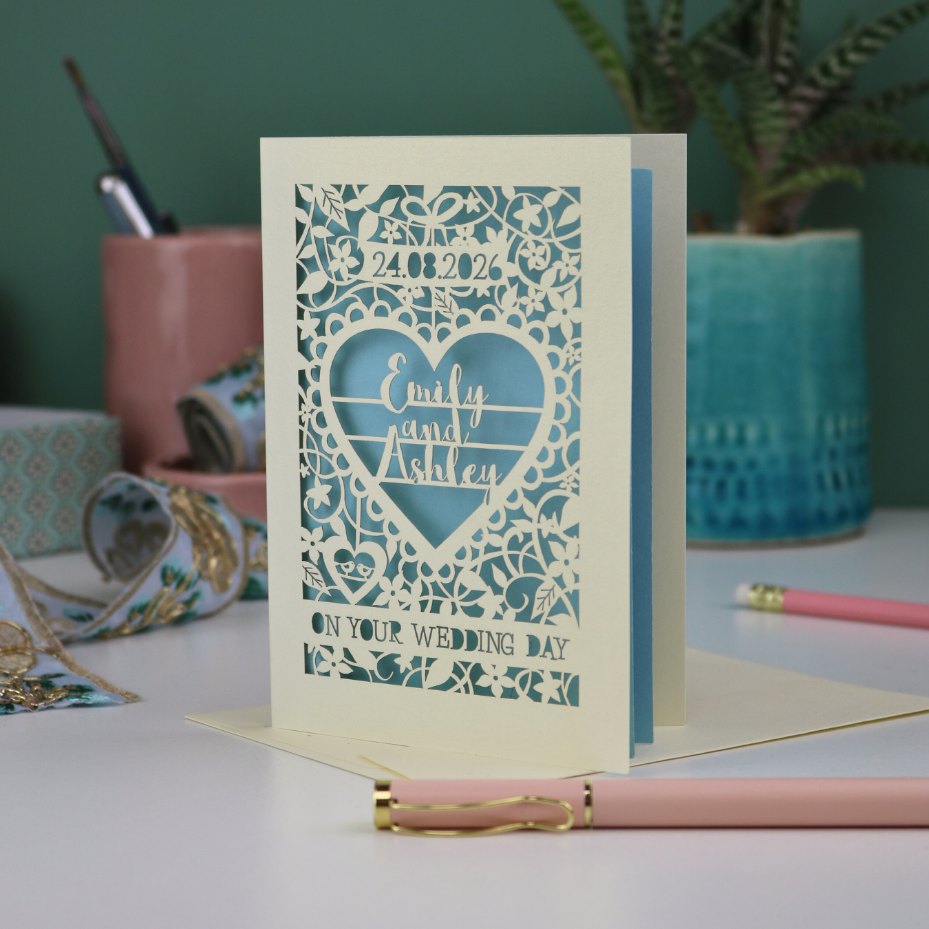 A personalised laser cut 'On your wedding day' card with the  date, floral design and  heart shaped border around the names "Emily and Ashley"