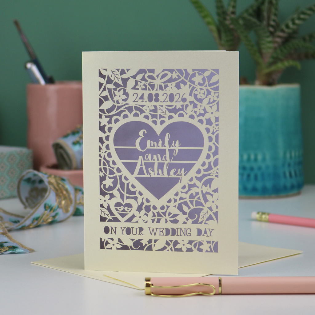 Wedding card with personalized text on a desk with stationery items.
