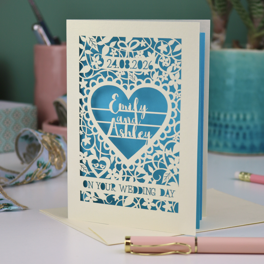 Wedding card with personalized text on a desk with stationery items.