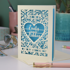 Wedding card with personalized text on a desk with stationery items.
