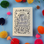 Personalized Christmas card with 'In Our First Christmas 2025' text, surrounded by colourful pom-poms on a blue background.