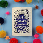 Personalized Christmas card with 'On Our First Christmas 2025' text, surrounded by colourful pom-poms on a blue background.