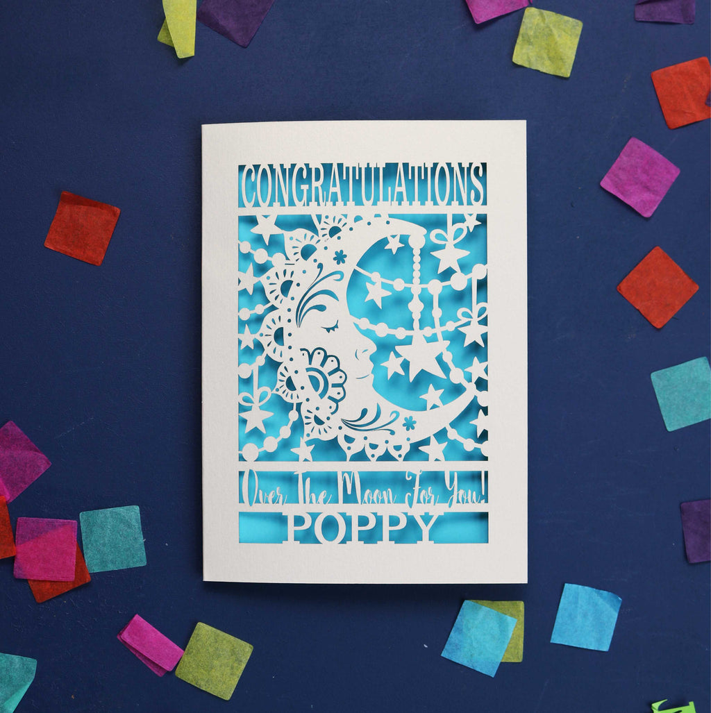 Laser cut congratulations card with a crescent moon and stars, with the words "Congratulations, over the moon for you" and personalised with a name