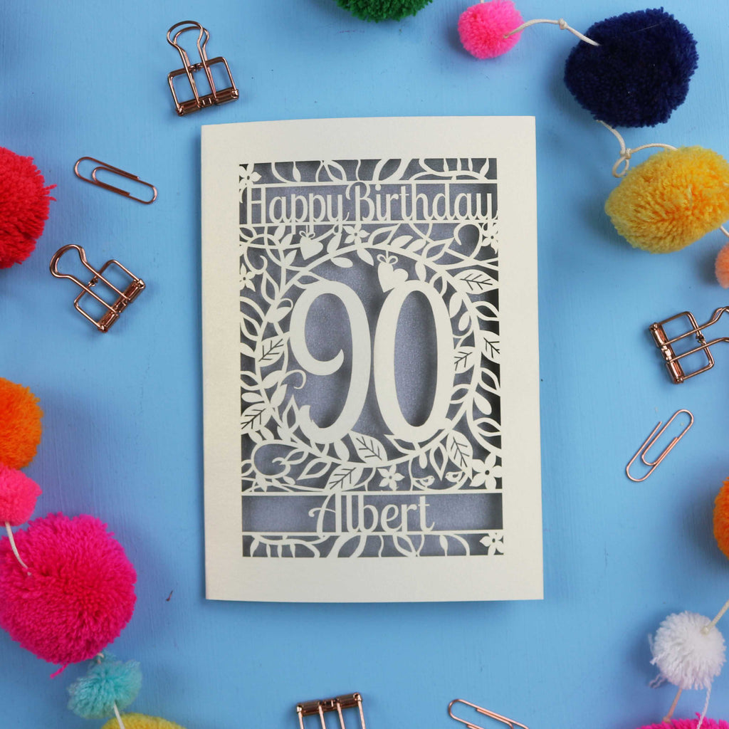 Birthday card with 'Happy Birthday 90 Albert' on a blue background with colourful pom-poms and paper clips.