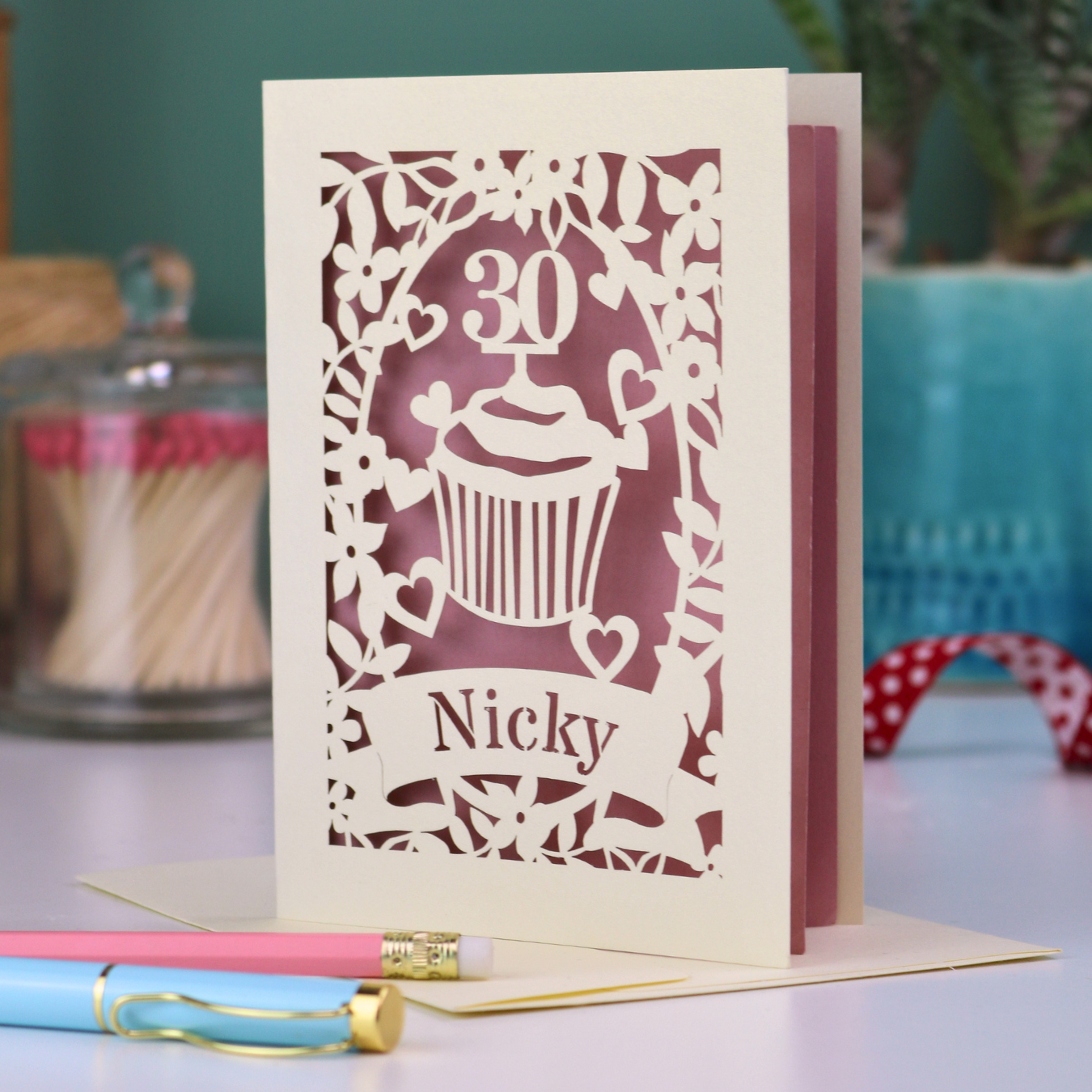 A laser cut 30th birthday card with cupcake design and personalised with a name in stencil font on a banner