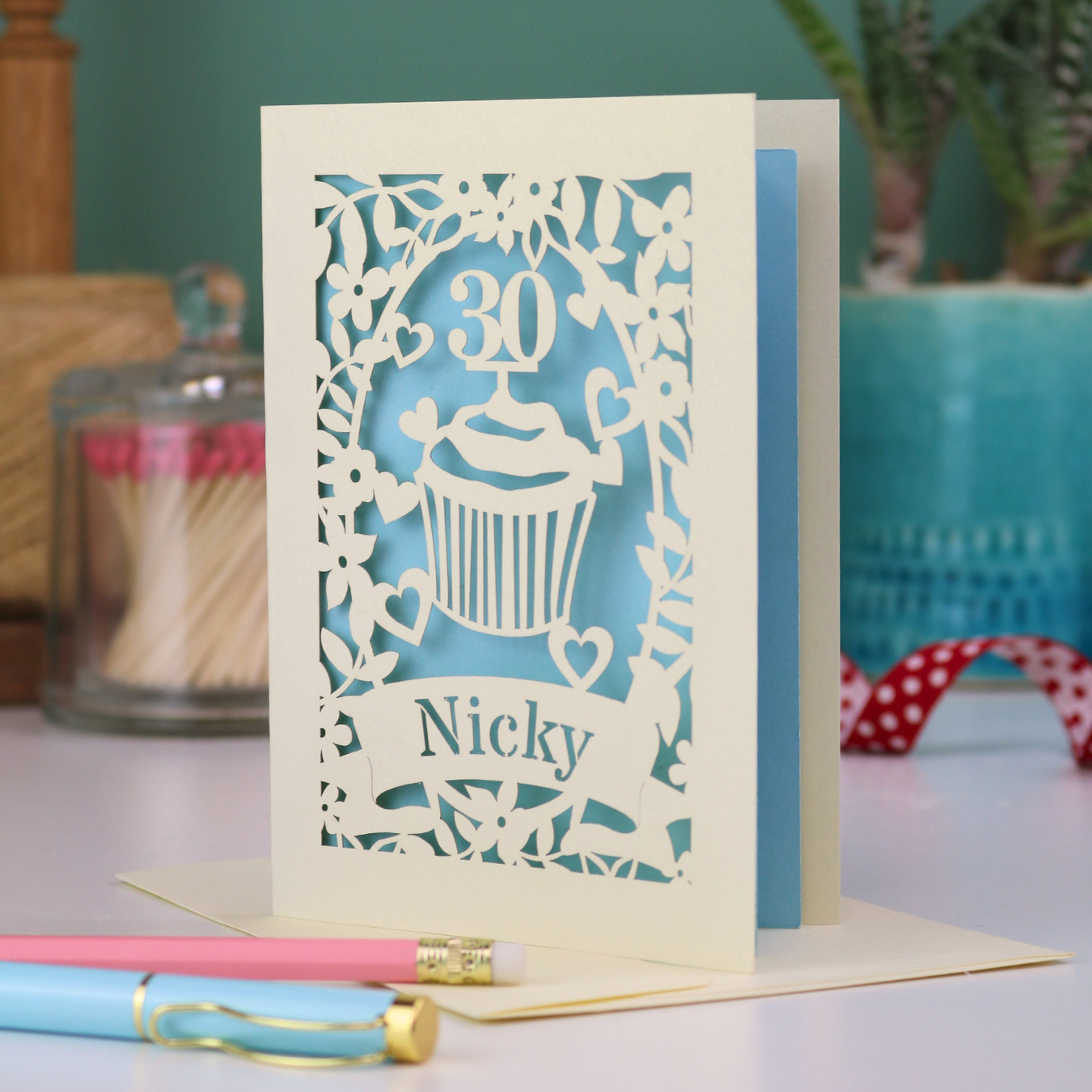 A laser cut 30th birthday card with cupcake design and personalised with a name in stencil font on a banner