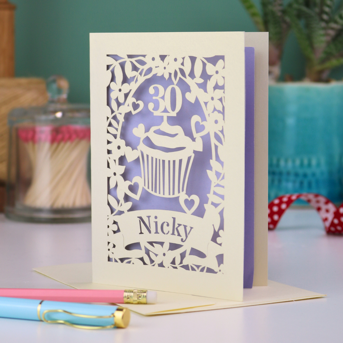 A laser cut 30th birthday card with cupcake design and personalised with a name in stencil font on a banner