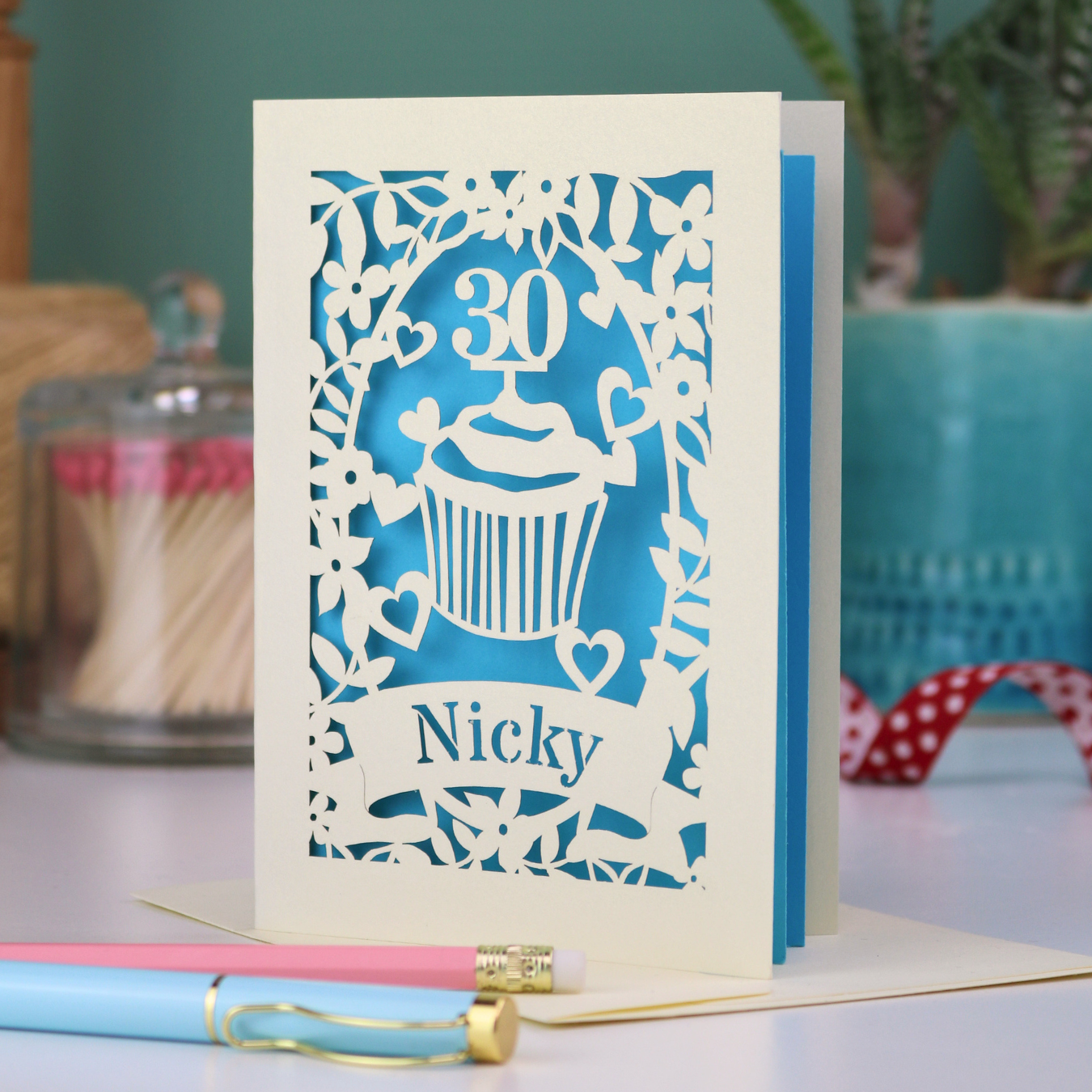 A laser cut 30th birthday card with cupcake design and personalised with a name in stencil font on a banner
