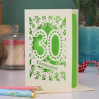 A paper cut out 30th birthday card with laser cut '30' design and personalised with the bane "Christopher" in cut out stencil writing on a banner shape.