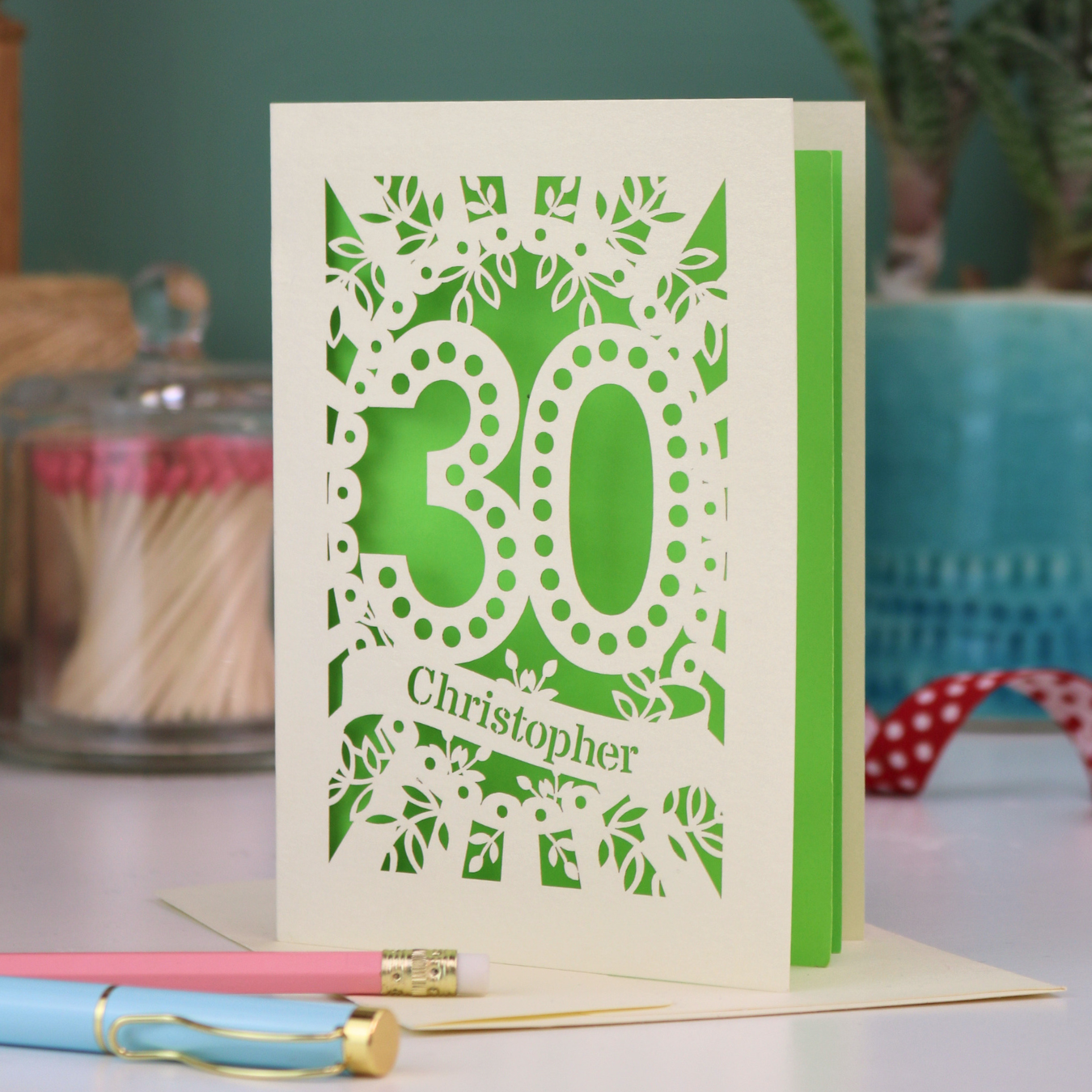 A paper cut out 30th birthday card with laser cut '30' design and personalised with the bane "Christopher" in cut out stencil writing on a banner shape.