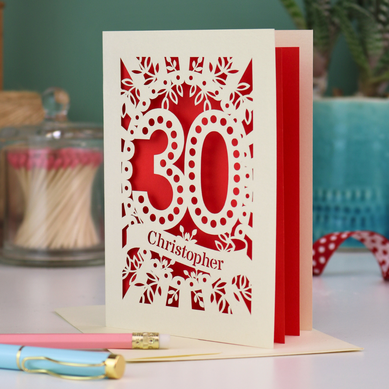 A paper cut out 30th birthday card with laser cut '30' design and personalised with the bane "Christopher" in cut out stencil writing on a banner shape.