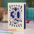A paper cut out 30th birthday card with laser cut '30' design and personalised with the bane "Christopher" in cut out stencil writing on a banner shape.