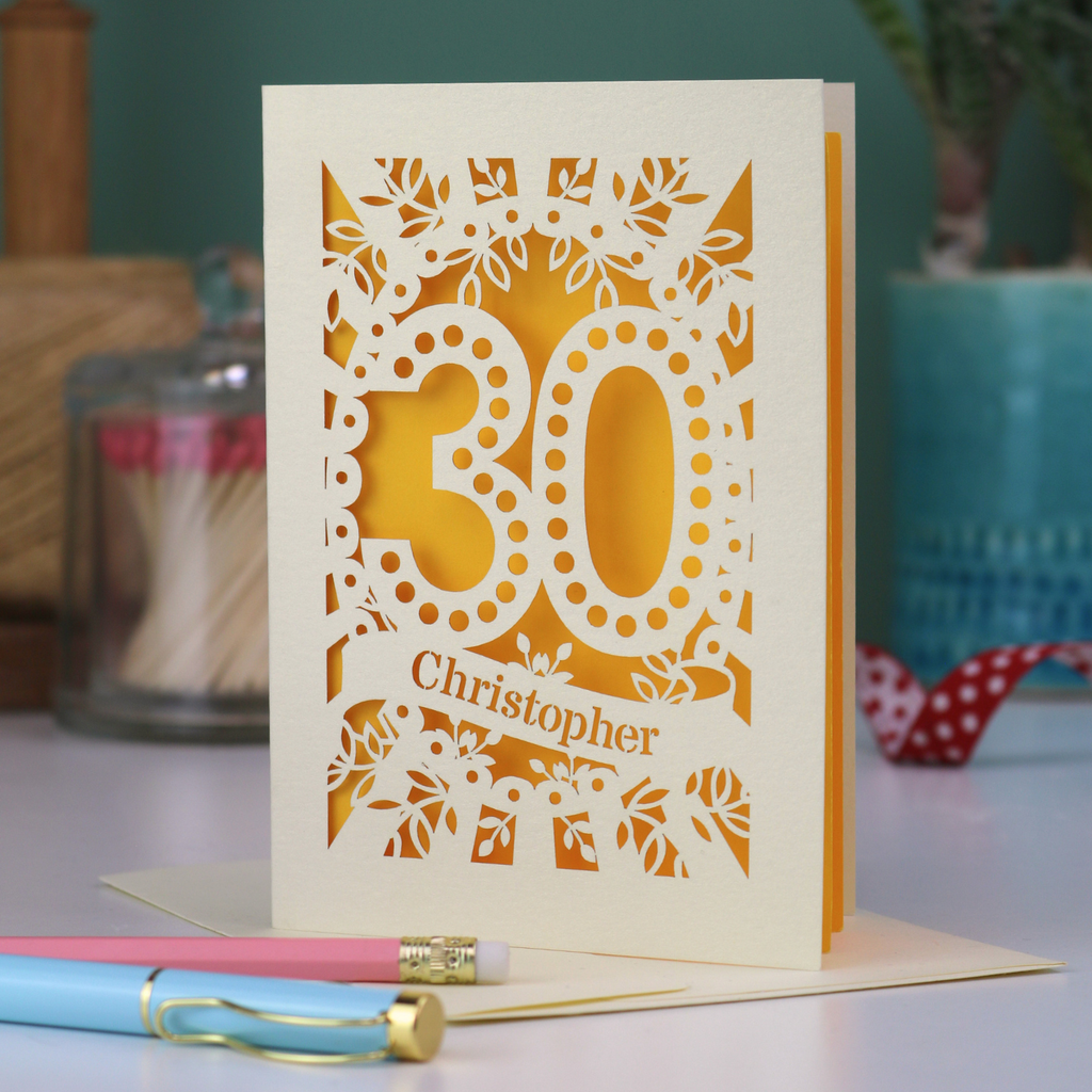 A paper cut out 30th birthday card with laser cut '30' design and personalised with the bane "Christopher" in cut out stencil writing on a banner shape.