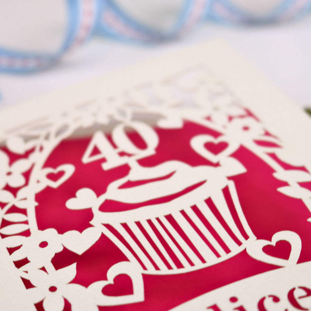 Decorative paper cutout with a cupcake design on a pink background