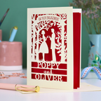 Engagement card with cut-out silhouettes of a couple, with "On your engagement" text and personalized names 'Poppy and Oliver'.