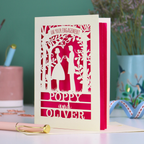 Personalised Couple Engagement card with cut-out silhouettes of a couple on a pink background, with 'Poppy and Oliver' printed below.